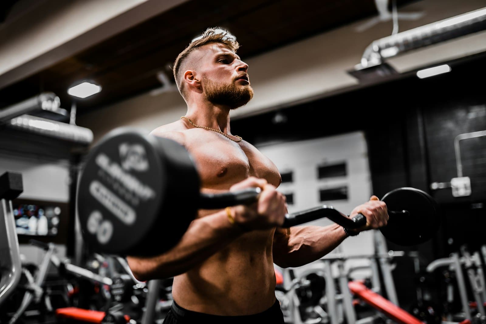 Lifter mid-rep with an EZ-curl bar in a studio setting